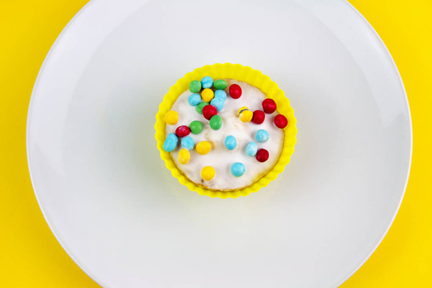 黄色の背景にバニラつや消しカップケーキ - 写真・画像