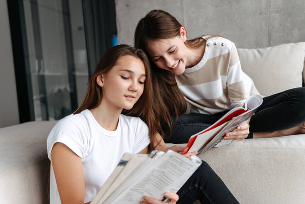 Two cheerful teenager girls friends sitting at home - Zdjęcie, obraz