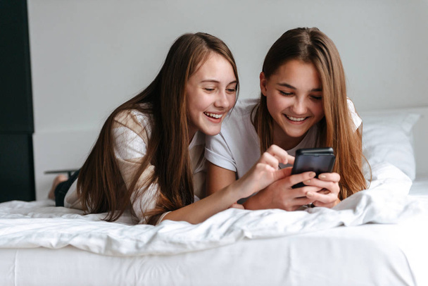 Two cheerful young teenage girls using mobile phone - Φωτογραφία, εικόνα