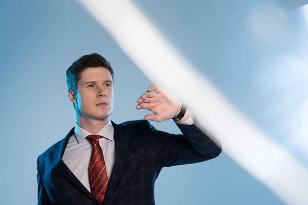 selective focus of young handsome businessman gesturing on blue - Valokuva, kuva