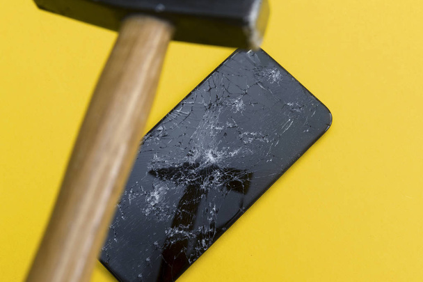 O martelo reflete-se na tela de telefone quebrada. Conceito de reparação telefone
 - Foto, Imagem