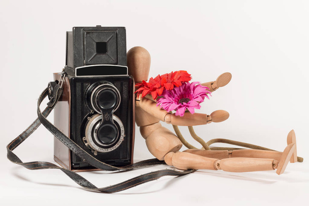 Fotocamera e manichino in legno con fiori su bianco
 - Foto, immagini