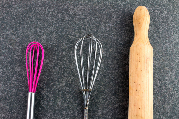 close-up shot of whisks with wooden rolling pin on stone kitchen surface - Photo, Image