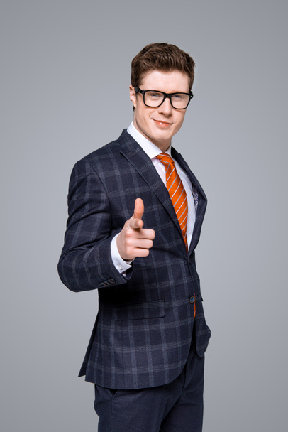 successful stylish businessman smiling and pointing at you isolated on grey - Foto, Imagem