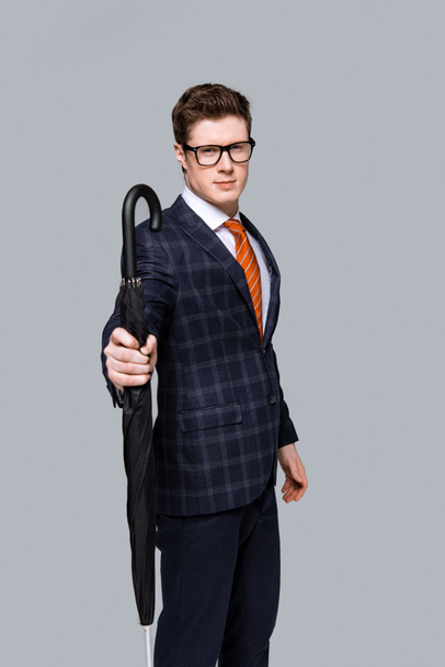 studio shot of stylish businessman posing with umbrella isolated on grey - Φωτογραφία, εικόνα