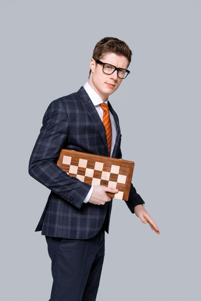 handsome young businessman with chess board isolated on grey - Photo, Image
