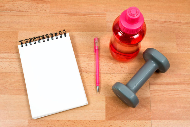 sport equipment and notepad on wooden background - Photo, Image