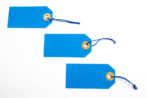 Ετικέτες μπλε χαρτί δεμένο με συμβολοσειρές που απομονώνονται σε λευκό - Φωτογραφία, εικόνα
