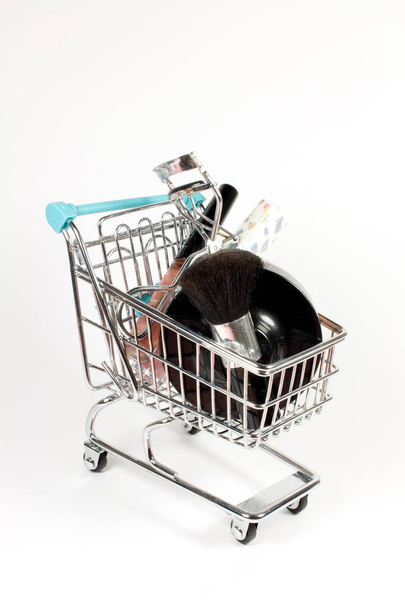 Cosmetics and Makeup tools in little shopping cart on white background - Photo, Image