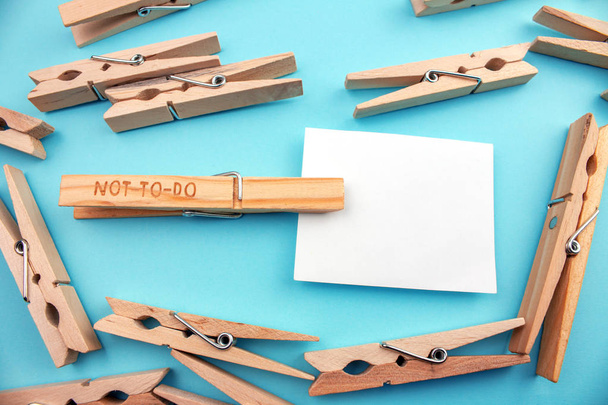 wooden clothespins with not to do symbol and empty card on blue background - Photo, Image