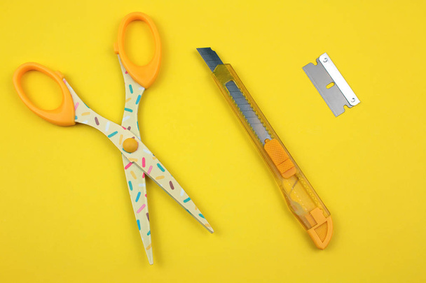 Yellow Plastic Cutter, scissors and blade on Paper background - Φωτογραφία, εικόνα