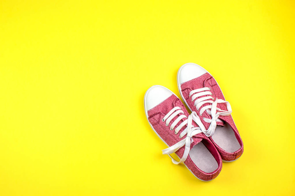 pair of vibrant sneakers on yellow background  - Фото, изображение
