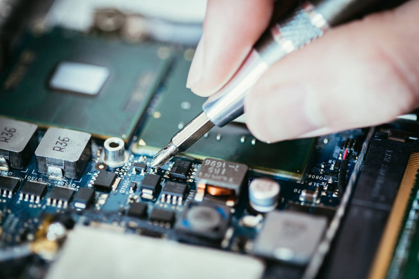 Technician is fixing a computer circuit board, hand and screwdri - 写真・画像