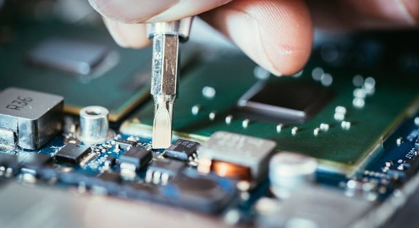 Technician is fixing a computer circuit board, hand and screwdri - Fotó, kép