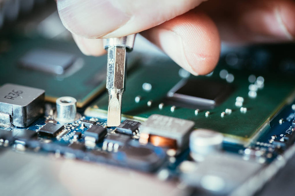 Technician is fixing a computer circuit board, hand and screwdri - Фото, изображение