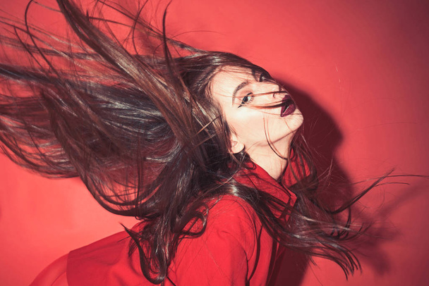Lady with make up waving her hair. Woman with stylish makeup and long hair posing in total red outfit. Fashion concept. Girl on mysterious face in red formal jacket, red background. - Фото, изображение