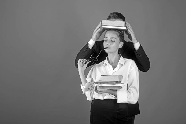 Education in knowledge day. Literature lesson and reading grammar book. Teacher man and girl hold book pile on head. Back to school and home schooling. School time of daughter and father in library - Fotoğraf, Görsel