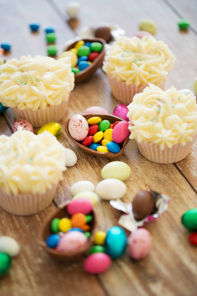 cupcakes with chocolate eggs and candies on table - Zdjęcie, obraz