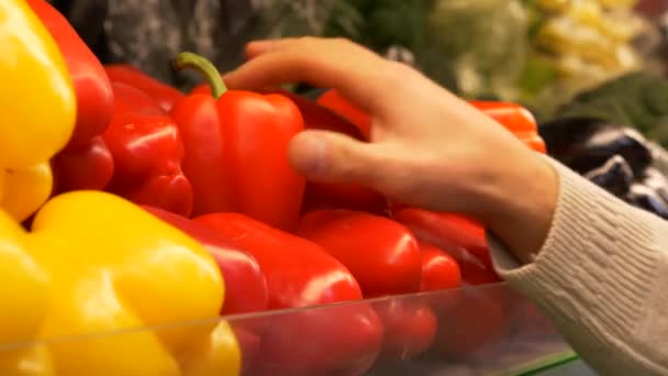 Young guy chooses red bell pepper in the supermarket. Hand takes red pepper from the counter in the store. Healthy food. 4K footage - Footage, Video