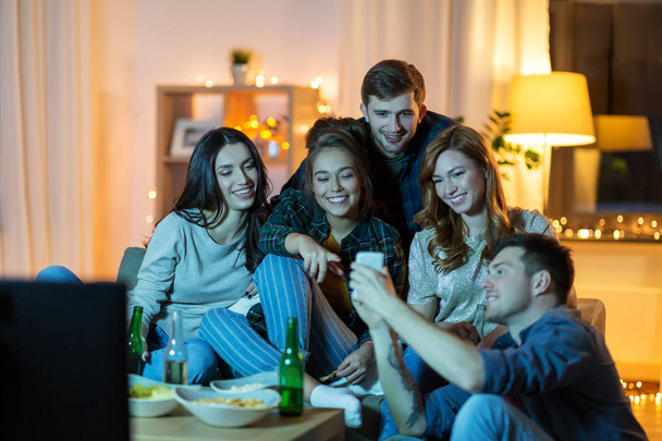 přátelé s smartphone sledování televize u vás doma - Fotografie, Obrázek