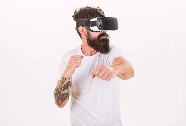 Man with beard in VR glasses fighting, white background. VR gadget concept. Guy with head mounted display fight in virtual reality. Hipster on busy face exploring virtual reality with modern gadget - Foto, Bild