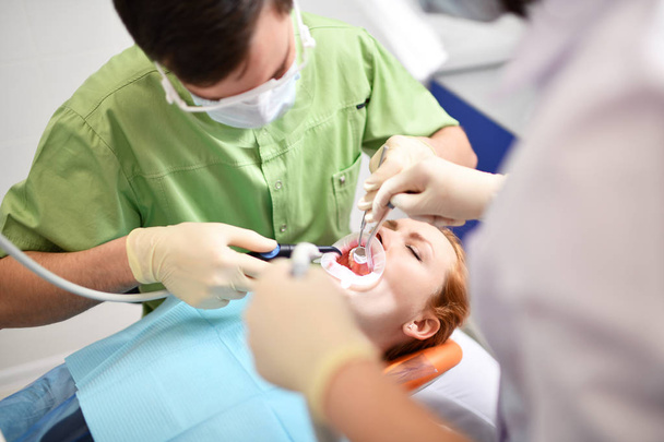 Οδοντίατρος που αρχίζει κοινή λειτουργία καθαρισμού του γυναικείου στόματος - Φωτογραφία, εικόνα
