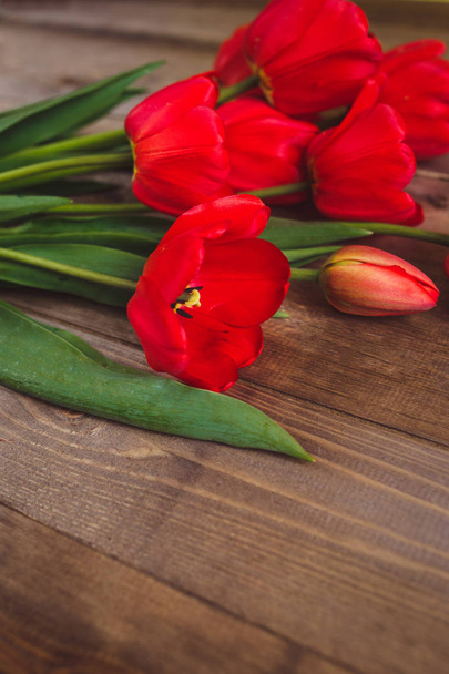 Row of red tulips on wooden background with space for message. Mothers Day background. Top view. Flat lay - Foto, imagen