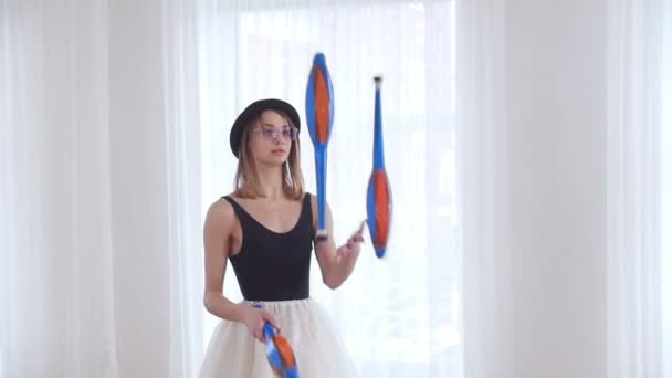Young woman in a black hat juggling in bright studio - Footage, Video