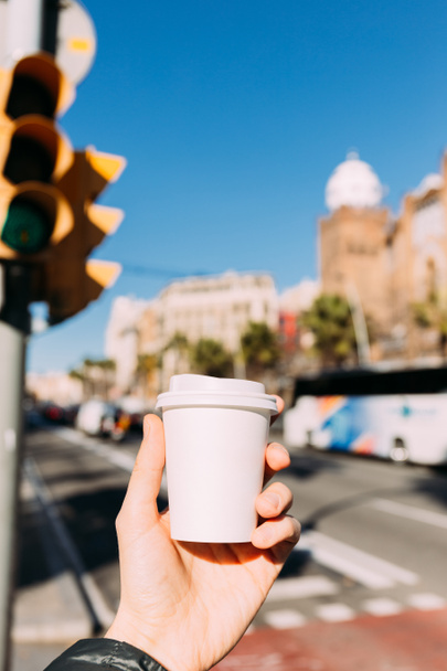 selective focus of male hand with paper cup, urban scene on background, barcelona, spain - Fotoğraf, Görsel