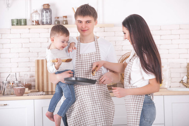 Wspólne gotowanie młodej rodziny. Mąż, żona i ich małe dziecko w kuchni. Rodzina - Zdjęcie, obraz