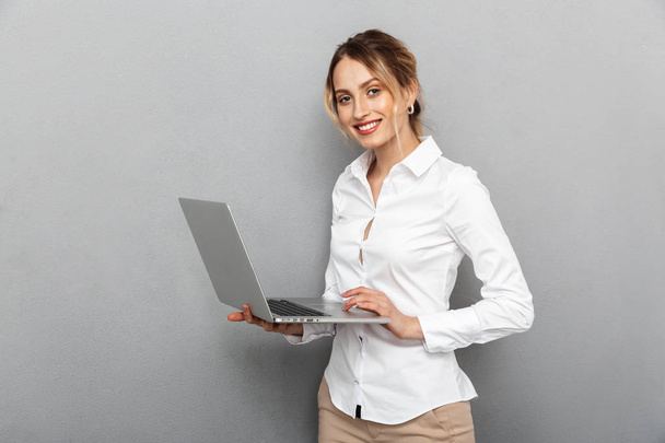 Photo of smart woman in formal wear standing and holding laptop  - Φωτογραφία, εικόνα