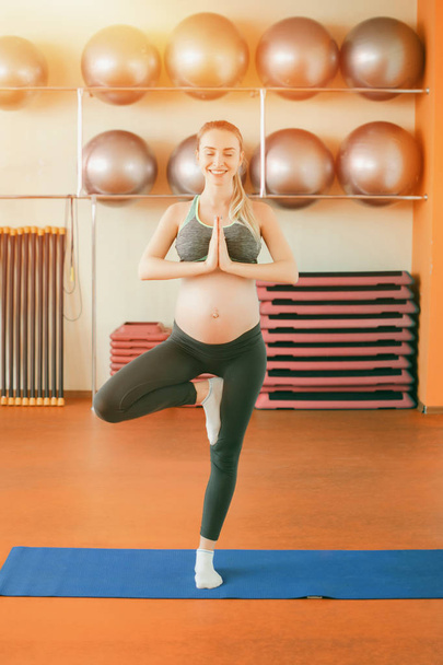 Jooga raskaana oleville naisille. Nuori kaunis raskaana tyttö seisoo yhdellä jalalla
 - Valokuva, kuva
