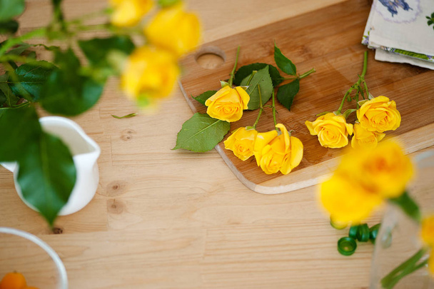 Floral flat lay composition process of making bouquet. Fresh yelow flowers on white wooden table, top view. - Foto, Bild
