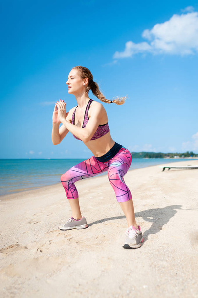 молодая женщина, разрабатывающая ядро и глюкозу с упражнениями на приседание на пляже
. - Фото, изображение