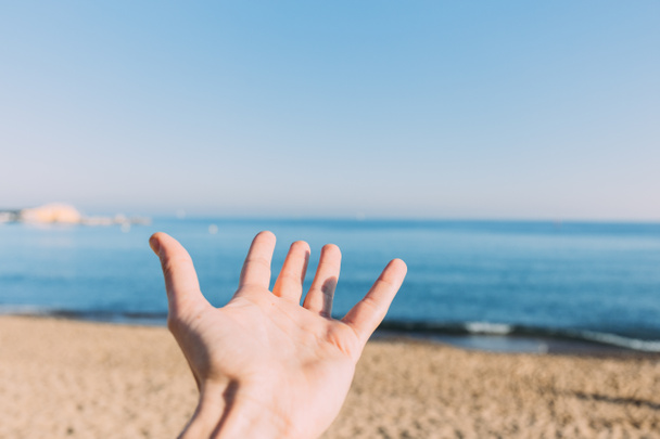 male hand on calm blue sea background, barcelona, spain - 写真・画像