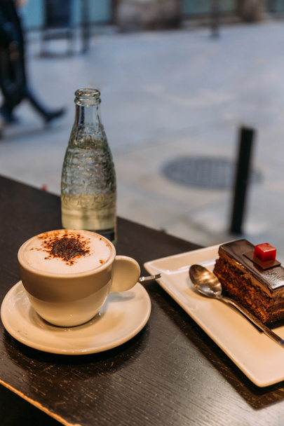 coffee cup, bottle of mineral water and saucer with cake on bar counter, barcelona, spain - Photo, Image