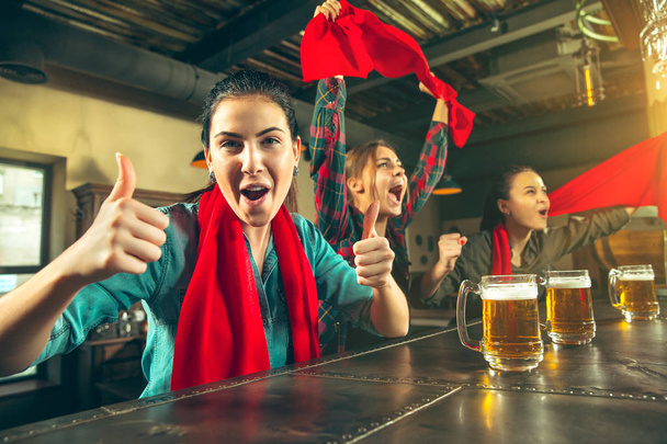 Sport, people, leisure, friendship and entertainment concept - happy football fans or female friends drinking beer and celebrating victory at bar or pub - Photo, image