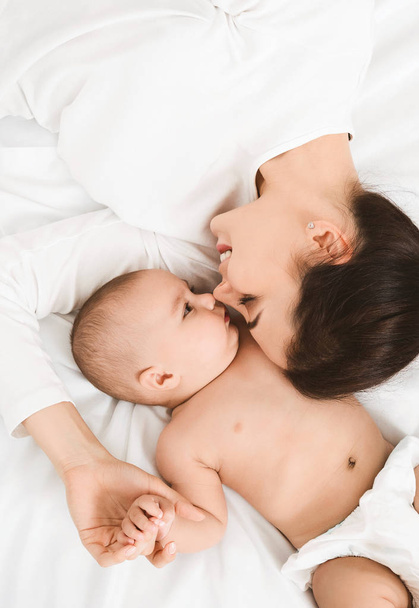 Maman et petit bébé couchés dans le lit nez à nez
 - Photo, image