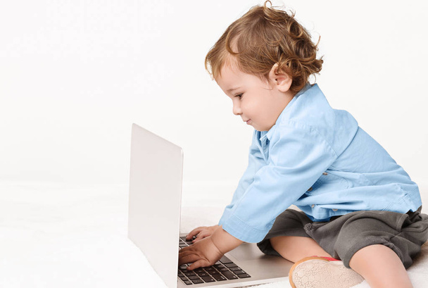 Niño lindo escribiendo en el teclado del ordenador portátil
 - Foto, Imagen