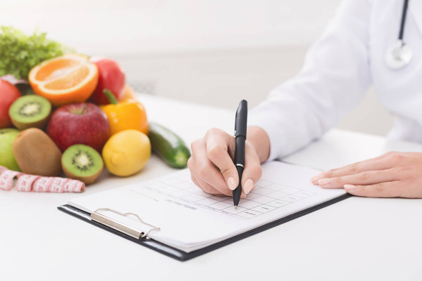 Nutricionista femenina médico escribir plan de dieta vegetal
 - Foto, imagen