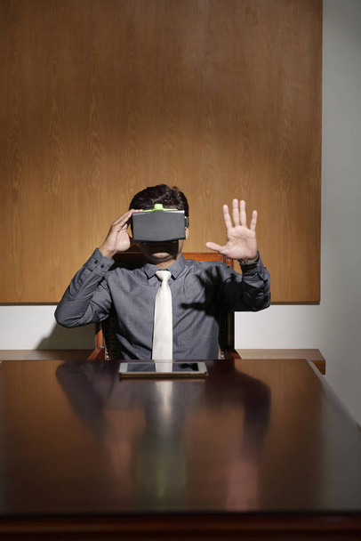 Homme d'affaires en réalité virtuelle lunettes assis à table dans la salle de réunion
 - Photo, image