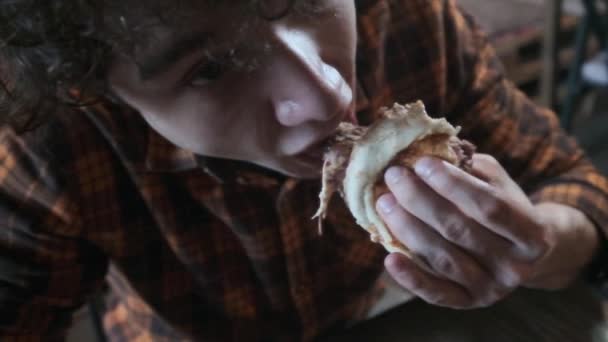 Kıç sakallı bir adam agresif ve kaba bir şekilde sandviç yiyor. Hızlı yemek yiyor. Obezite toplumun kavramı ve kötü beslenme. - Video, Çekim