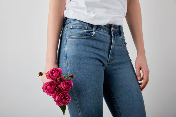 частковий вид на дівчину, що тримає рожеві троянди ізольовані на сірому
 - Фото, зображення