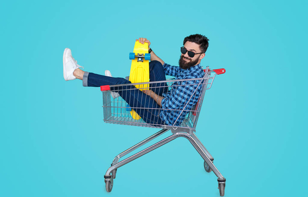 Guy with longboard sitting in shopping cart  - Фото, зображення