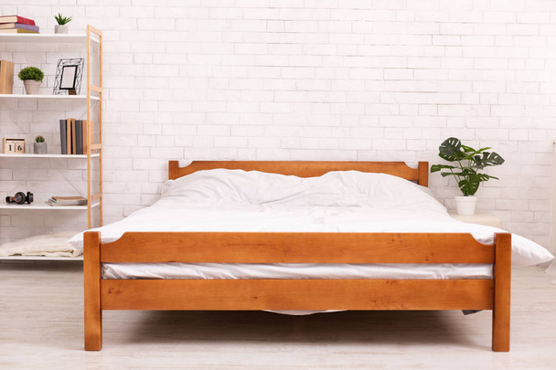 Wooden frame double bed with two pillows and blanket
 - Фото, изображение