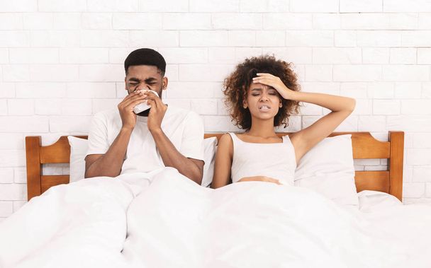 Άρρωστος Αφροαμερικανός ζευγάρι φυσώντας τη μύτη στο κρεβάτι - Φωτογραφία, εικόνα