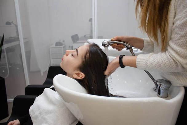 Femme appliquant le shampooing et massant les cheveux d'un client. Femme se faisant laver les cheveux dans un salon de coiffure
. - Photo, image