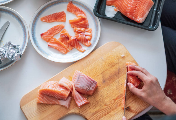 Chef à la main utilisant couteau tranche de saumon cru sur planche à découper
 - Photo, image