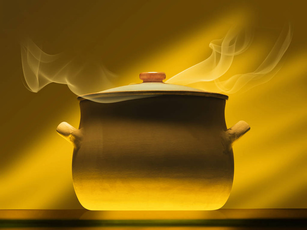 crock pot on mirror plate with steam, warm light - Foto, Bild