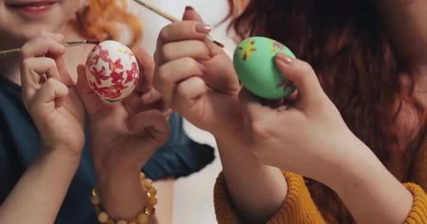Close up of mother and daughter hands coloring easter eggs with colors and brush. Colorful easter eggs. Preparation of the Easter - Кадры, видео